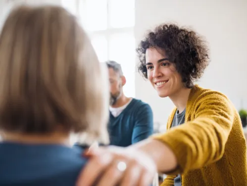 Woman comforting another woman in therapy session.