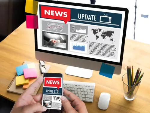 Laptop and smart phone with news items on the screen.