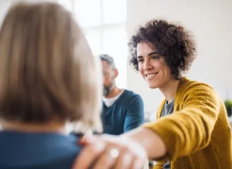 Woman comforting another woman in therapy session.