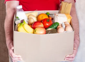 Box of food including bananas, milk, vegetables, and eggs.