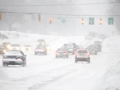 cars driving on partially plowed streets near a traffic light controlled intersection